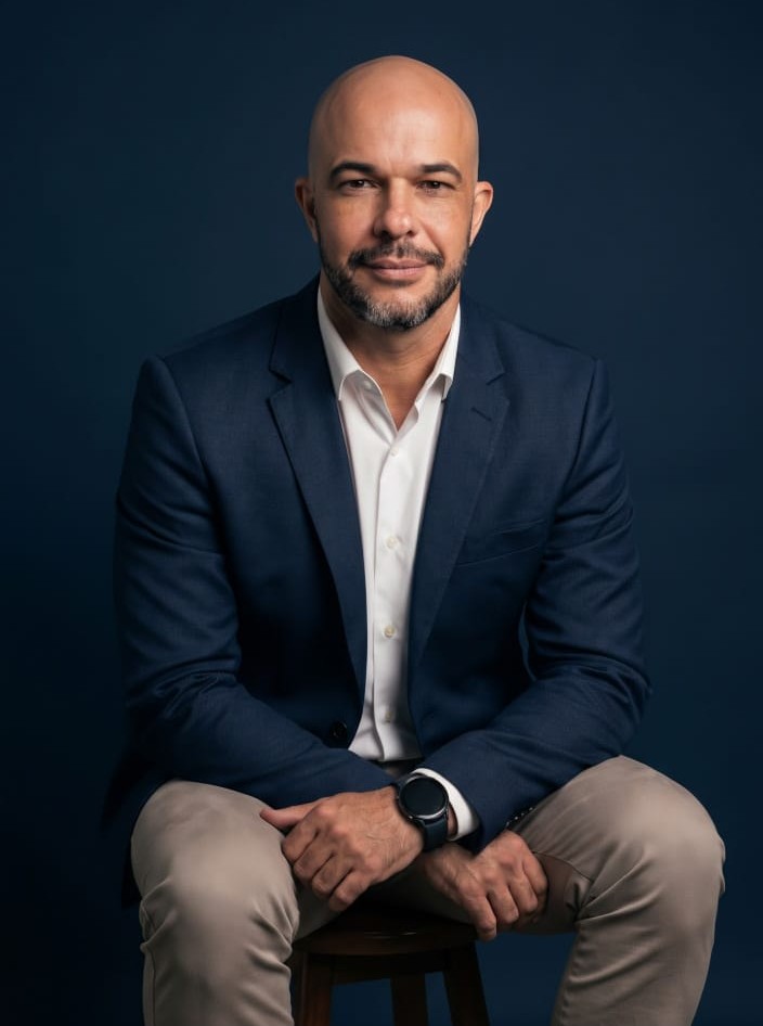 Evandro Veronezi, de terno azul-marinho, sentado em um banco de madeira